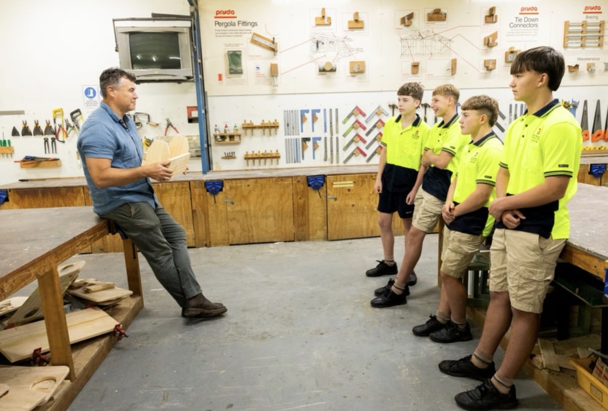 A teacher demonstrating a timber project to students in a workshop