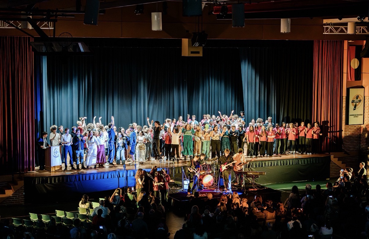 Musicians performing with a large group of performers on stage